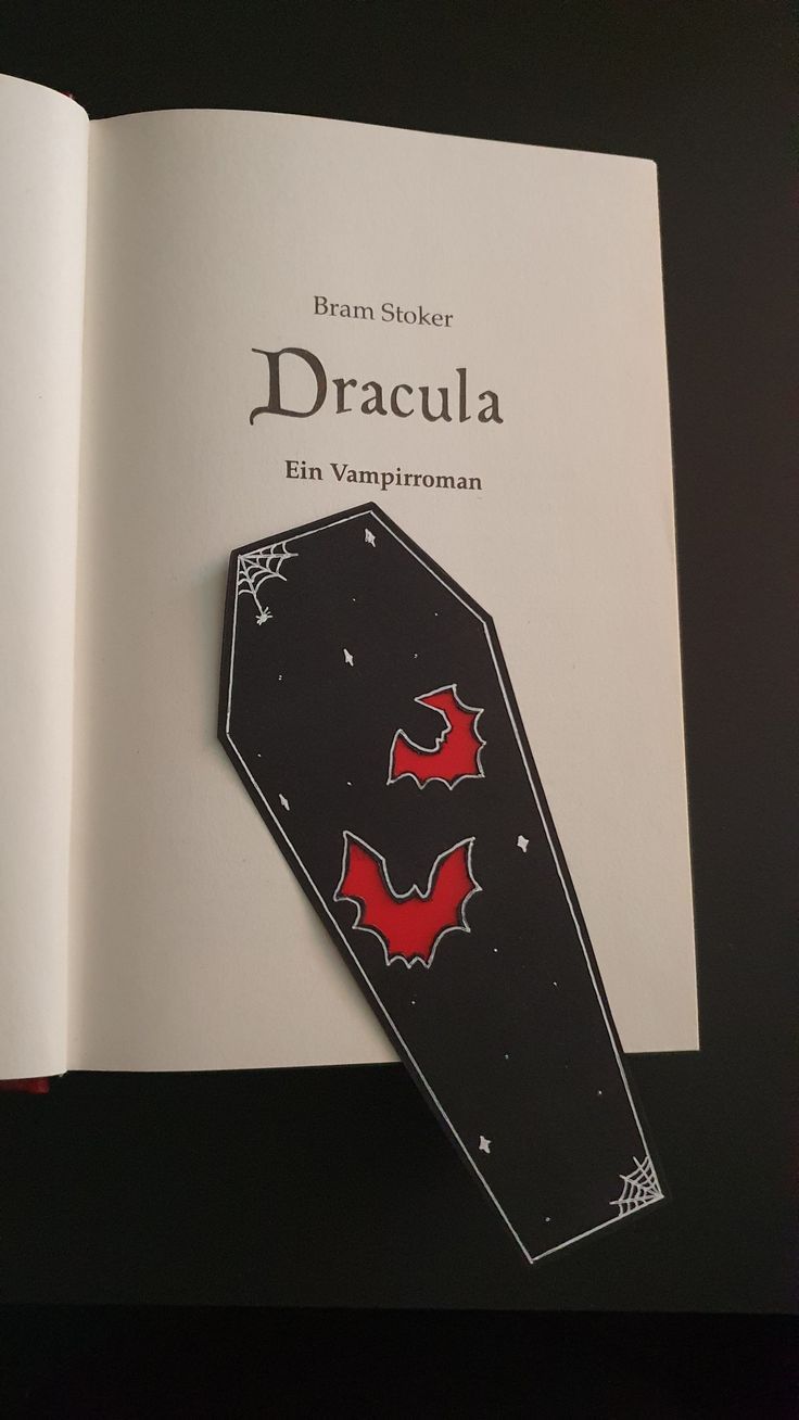 an open book with a bat on it's cover and the title dracula written in red