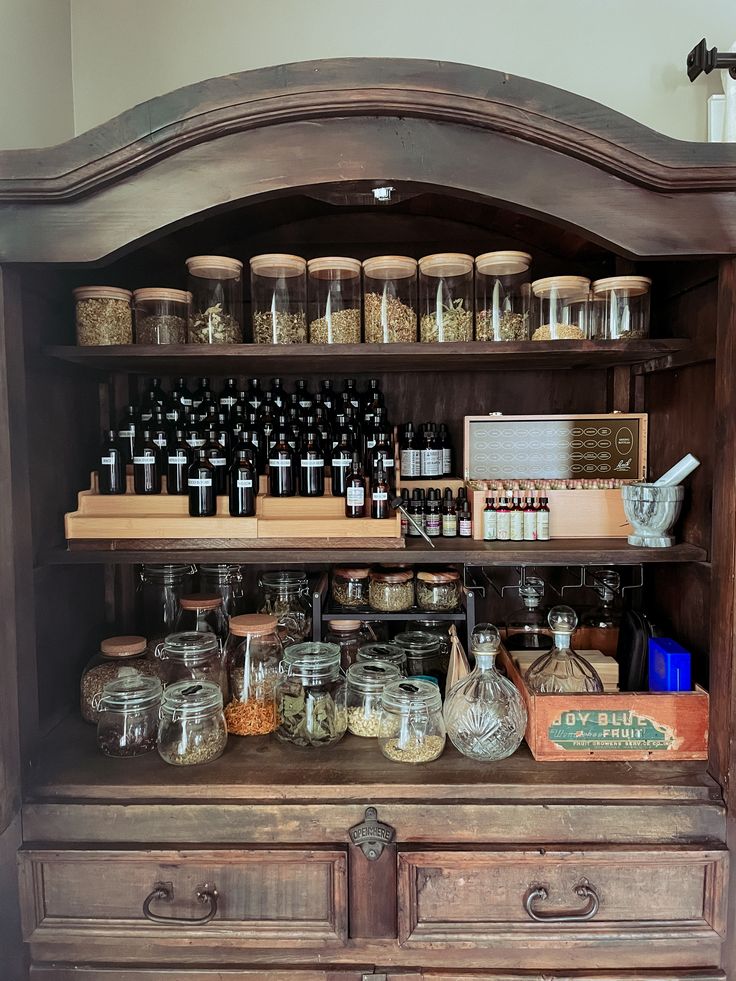 an old wooden cabinet filled with lots of bottles and jars on top of it's shelves