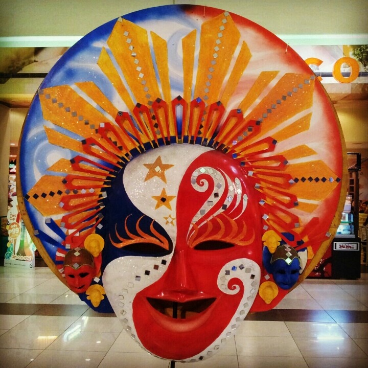 a colorful mask is on display in a shopping mall with an artistic face painted on it