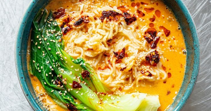 a bowl filled with noodles and vegetables on top of a table