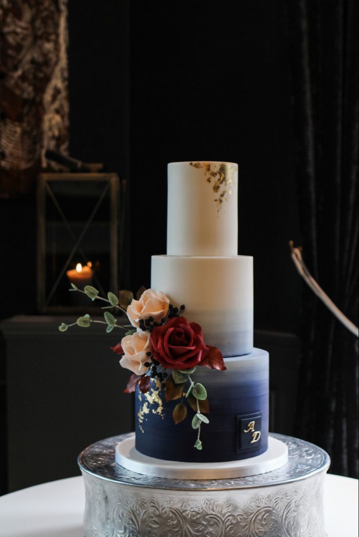 a three tiered wedding cake with flowers on the top and bottom, sitting on a silver platter