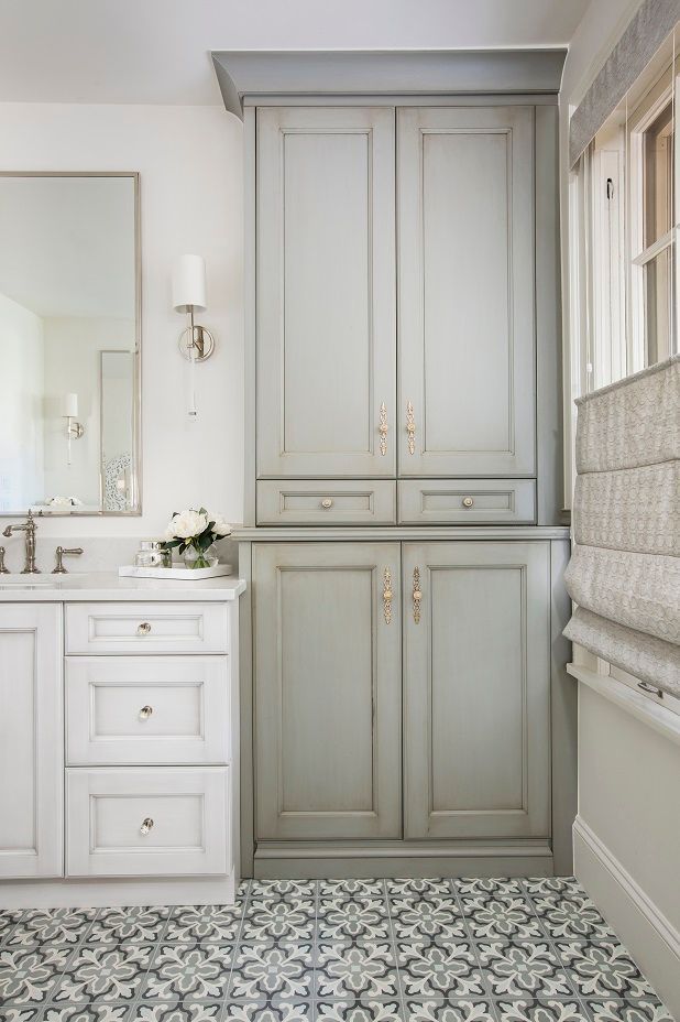 a bathroom with white cabinets and black and white floor tiles