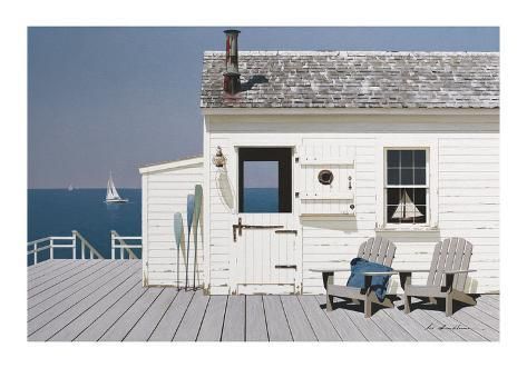 two adiron chairs sitting on a wooden deck next to a white building with a boat in the background