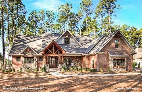 a large brick house with lots of trees in the front yard and two car garages