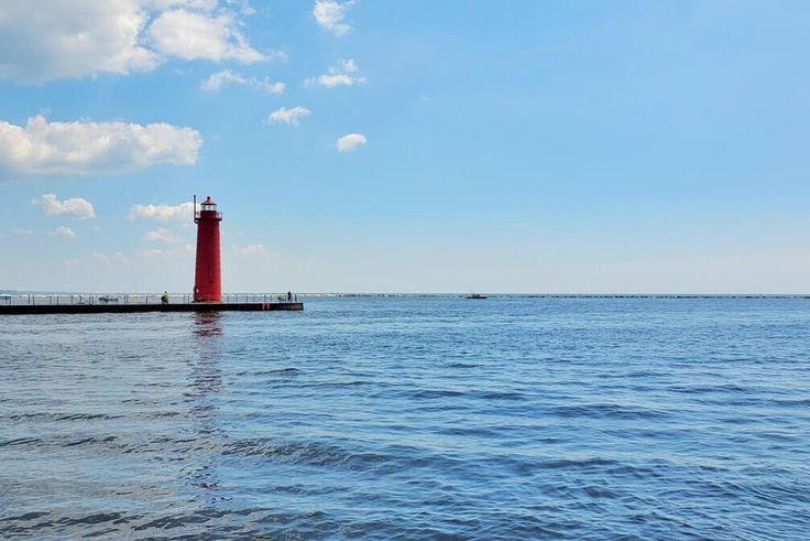 a red light house sitting on top of a body of water