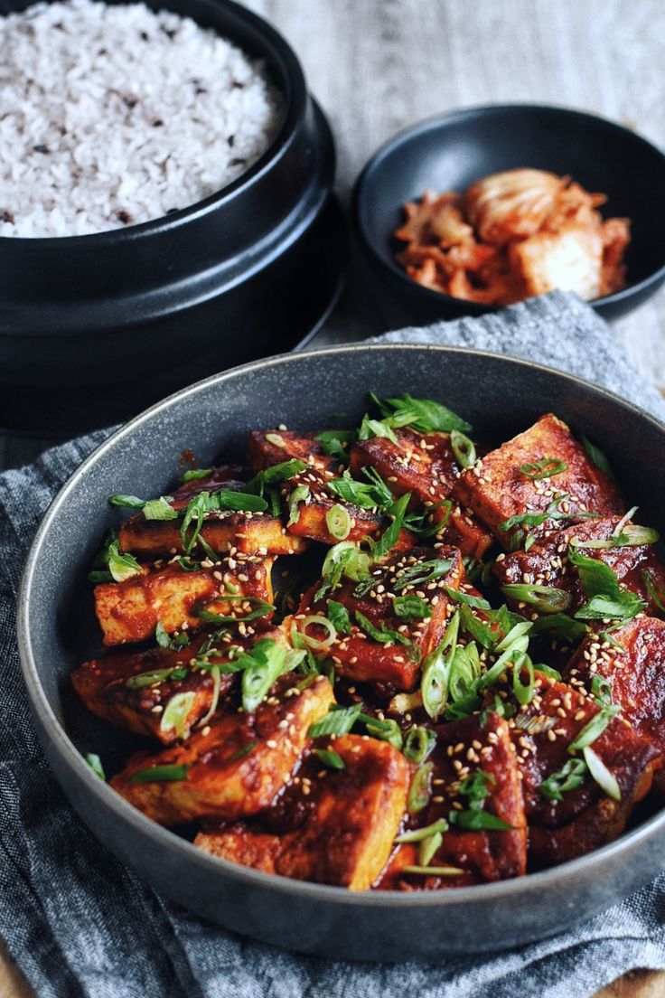 a bowl filled with tofu and rice next to other dishes