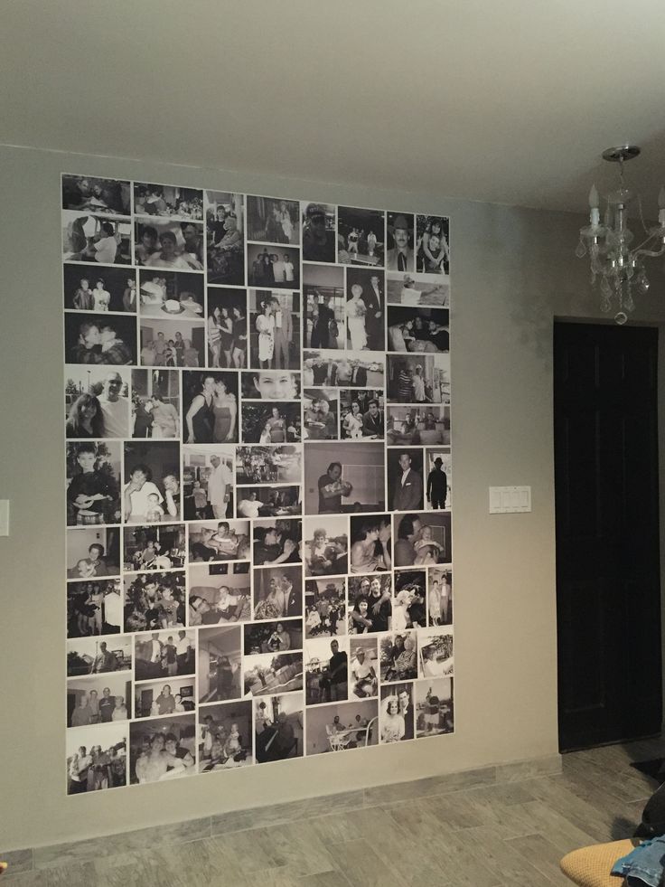 a wall with many pictures on it in a living room next to a door and chandelier