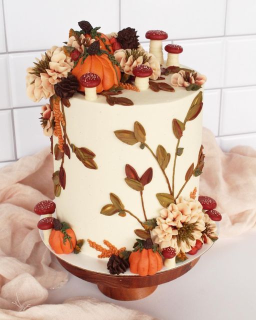 a white cake decorated with flowers and pumpkins