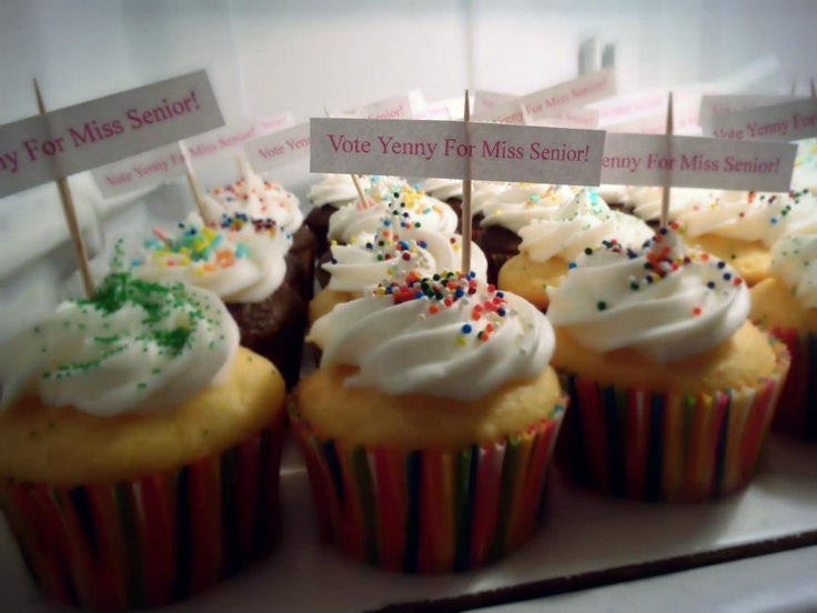 cupcakes with white frosting and colorful sprinkles are on display