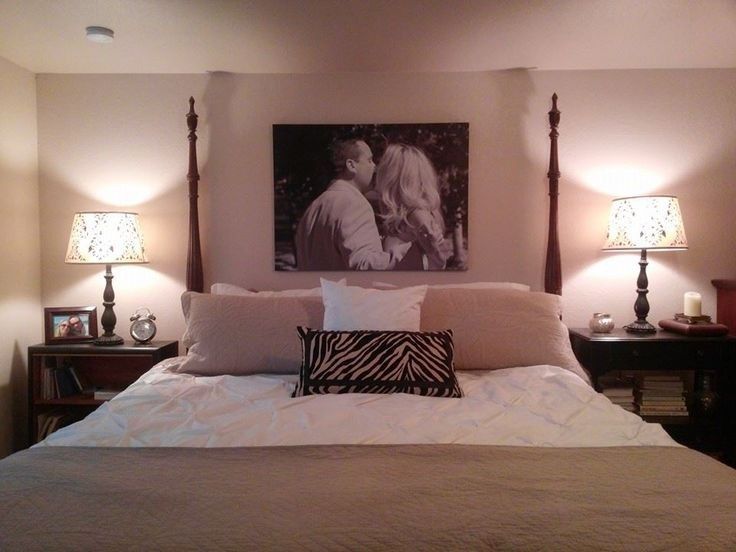 a bed with two lamps on either side of it and a painting above the headboard