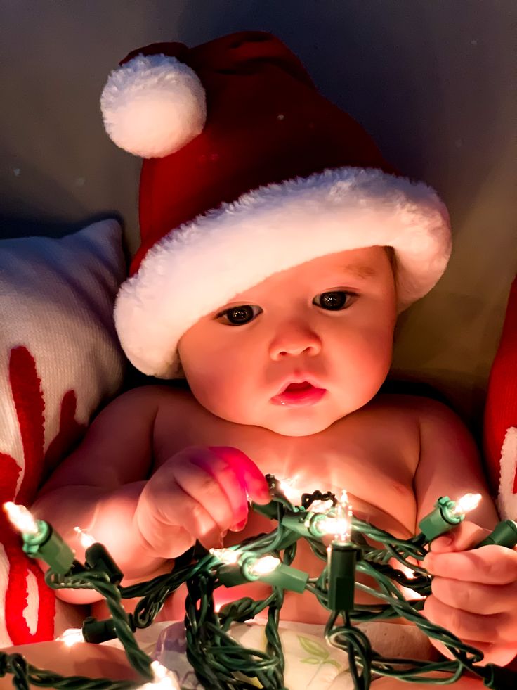 a baby wearing a santa hat is surrounded by christmas lights