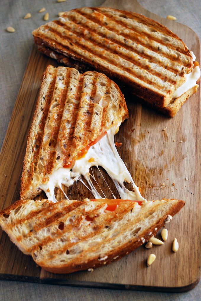 two grilled sandwiches on a wooden cutting board