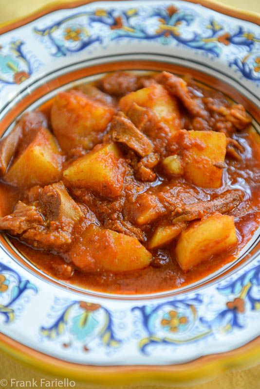 a close up of a plate of food with meat and potatoes in sauce on it