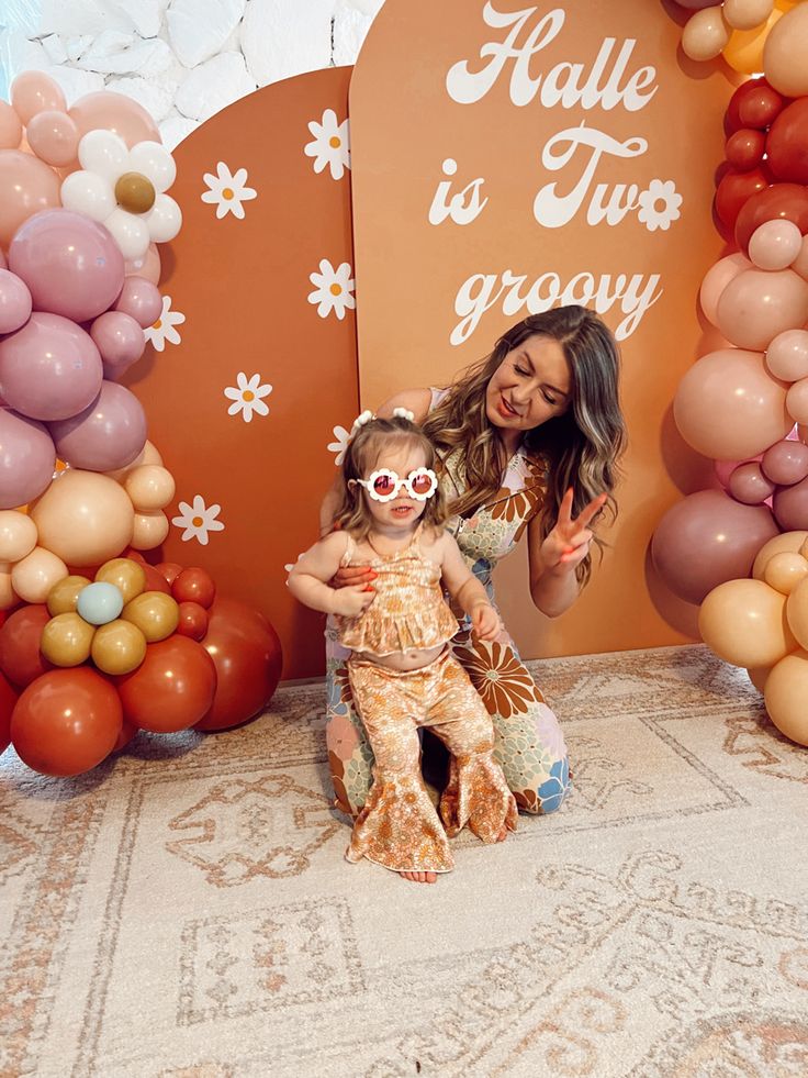 a woman and her daughter posing for a photo in front of balloon wall with balloons