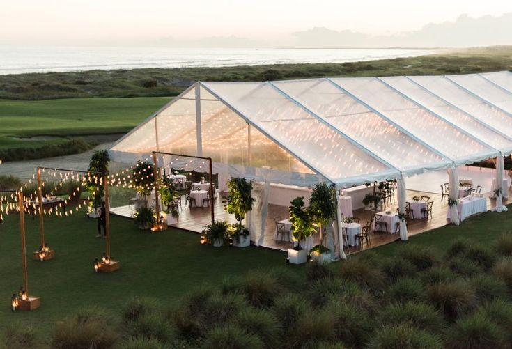 an aerial view of a tent set up for a wedding reception with string lights and greenery