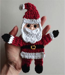 a hand holding a crocheted santa clause ornament