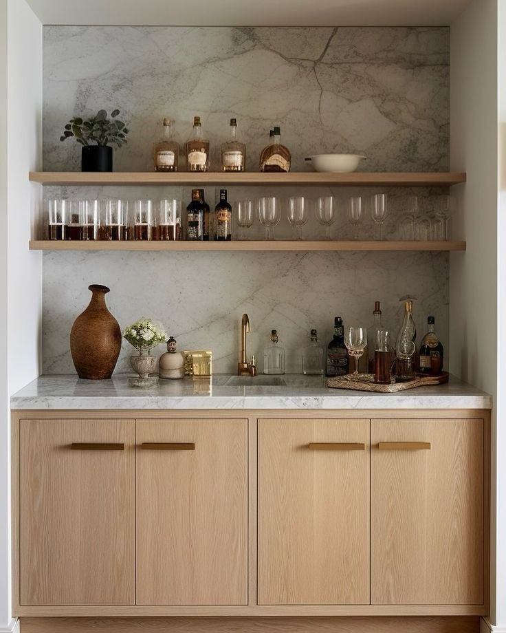 a kitchen with marble counter tops and wooden cabinets, filled with wine glasses on the shelves