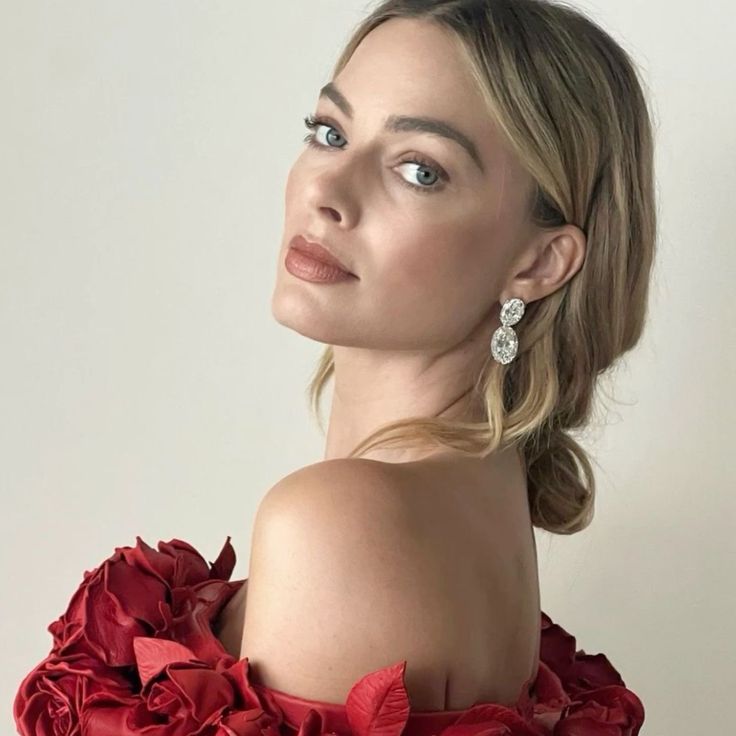 a woman in a red dress with flowers on her shoulder and one ear hanging down