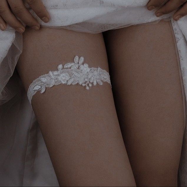 a close up of a woman's legs with white garter on her arm