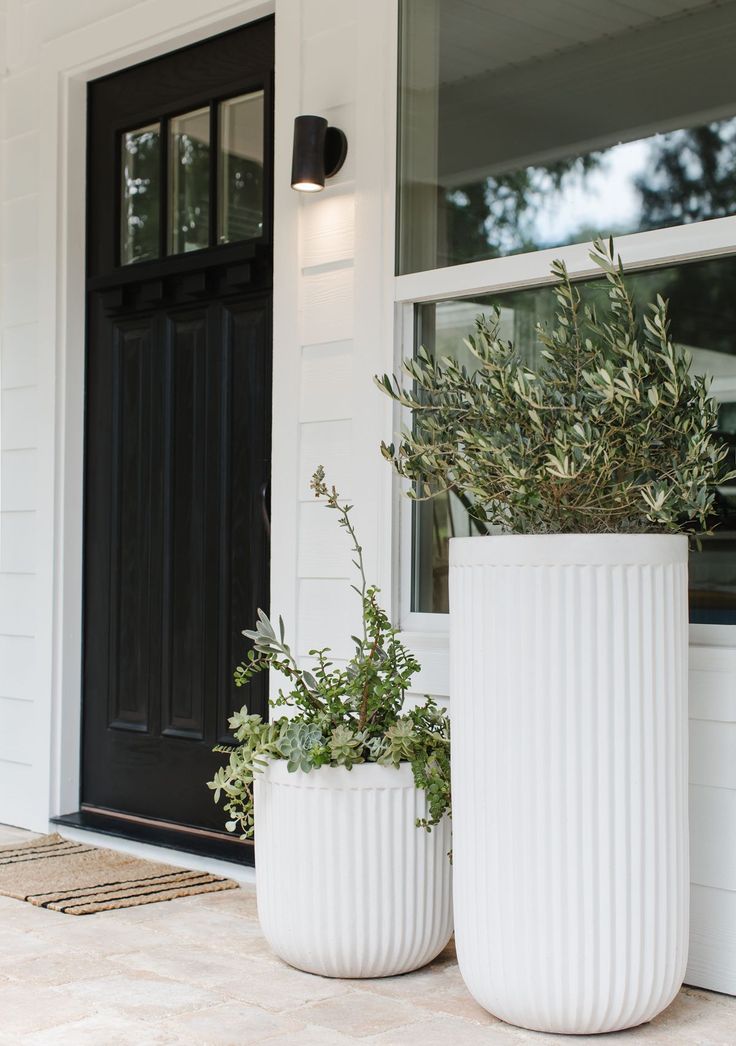 two white planters sitting on the side of a house