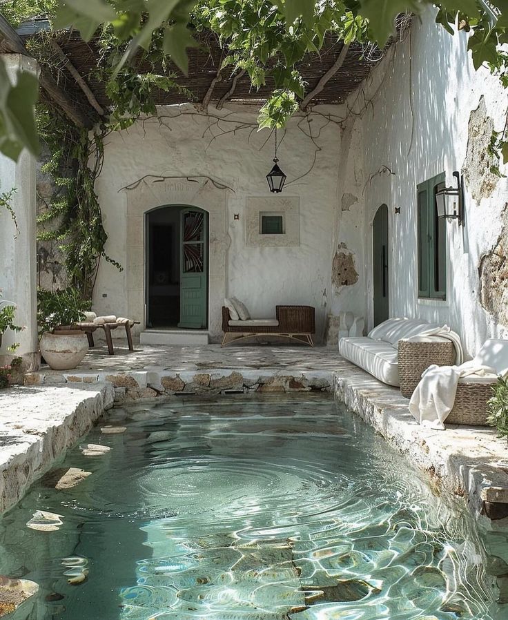 an outdoor swimming pool surrounded by greenery and stone steps leading up to a house