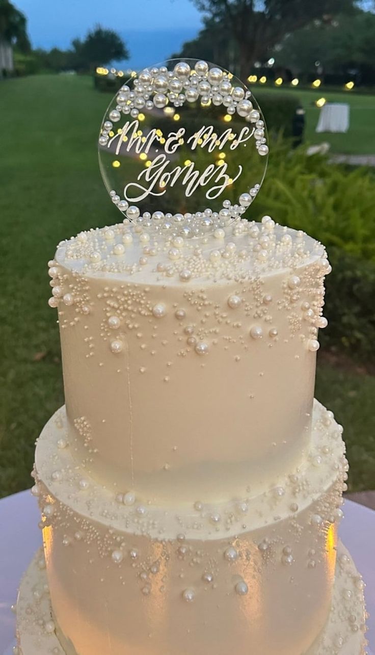 a three tiered wedding cake with an acrylic topper