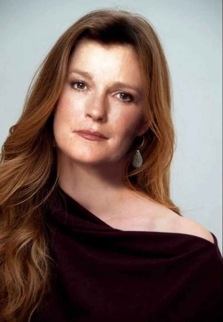 a woman with long red hair wearing a black dress and earrings is looking at the camera