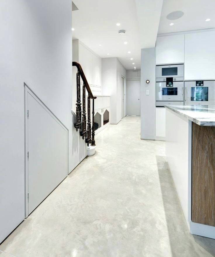 an empty white kitchen with stairs leading to the upper floor and another room in the background