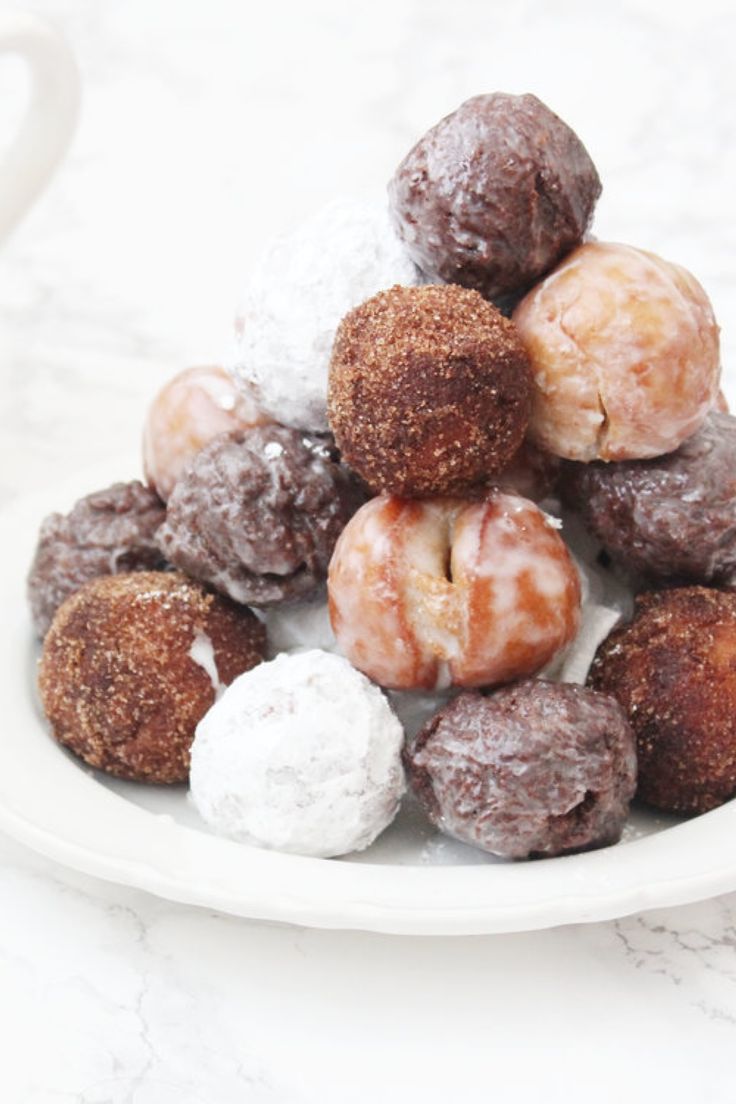 a white plate topped with donuts covered in powdered sugar next to a cup of coffee