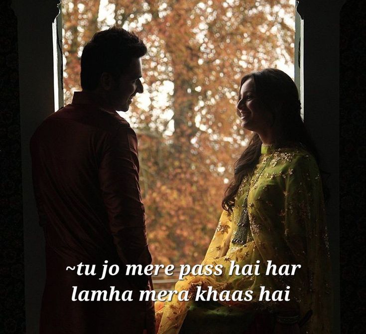 a man and woman standing next to each other in front of a window with trees