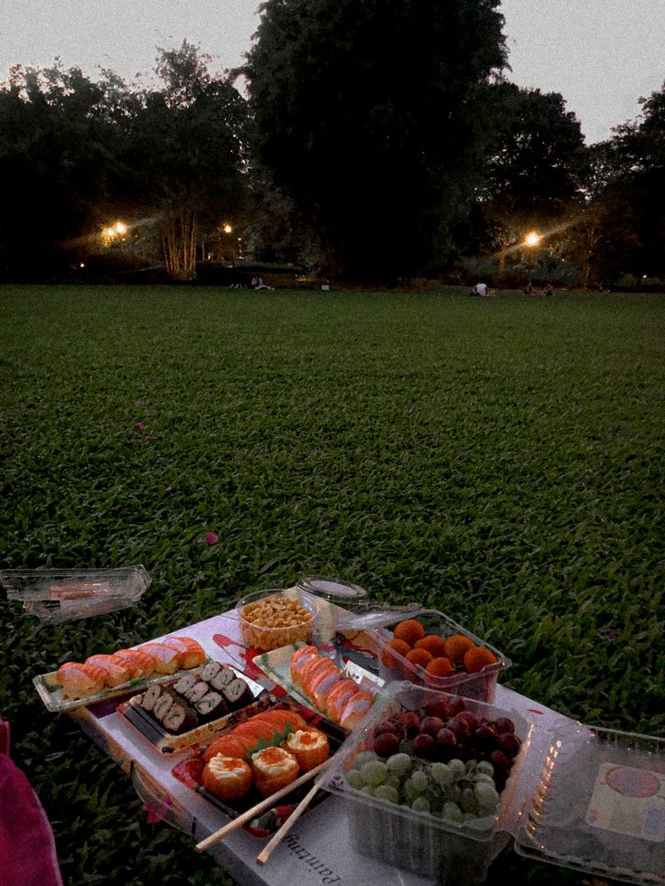 an assortment of sushi and other foods on a table in the middle of a field