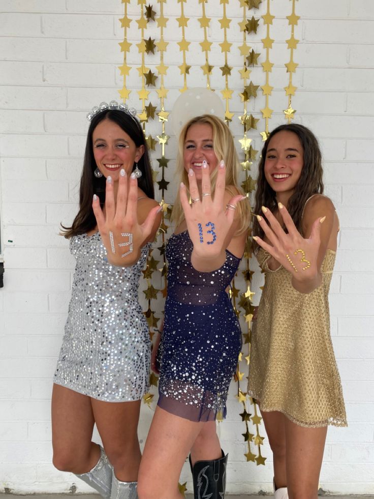 three girls posing for the camera with their hands in the air and one girl is holding her hand up