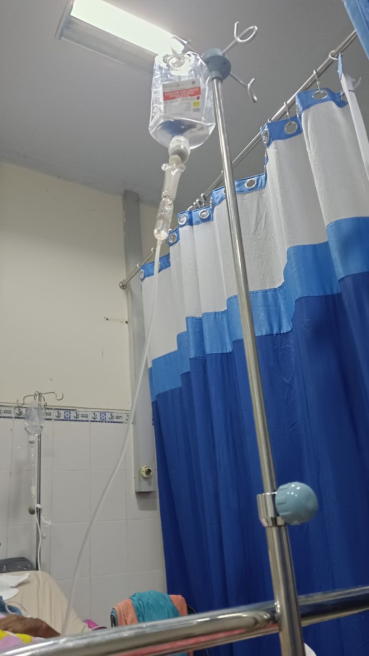 a hospital room with a blue and white shower curtain hanging from the ceiling next to a bed