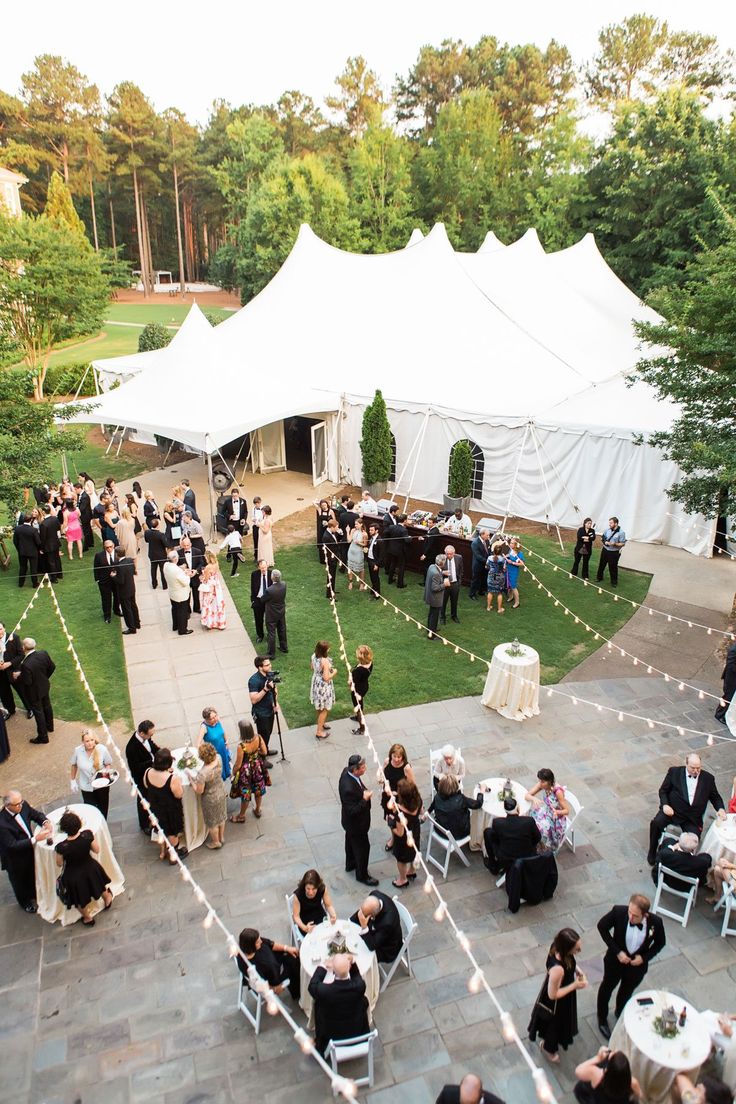 an aerial view of a wedding party in the backyard with white tents and string lights