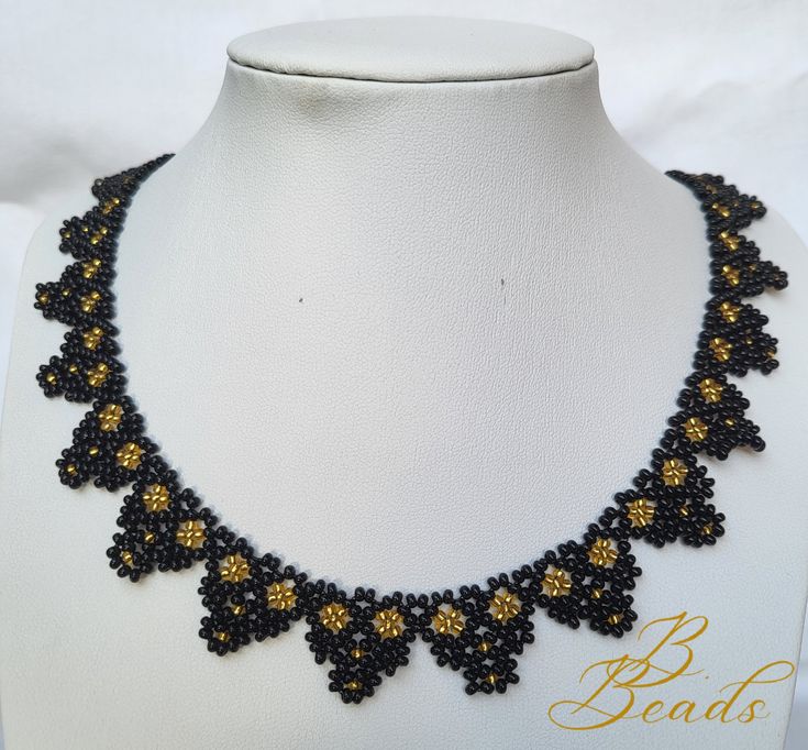 a black and yellow beaded necklace on a white mannequin neckline with gold beads