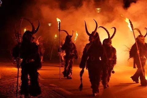 some people are walking around with torches in their hands and horned horns on their heads