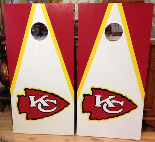 two cornhole game boards with the kansas chiefs logo on them, sitting on a table