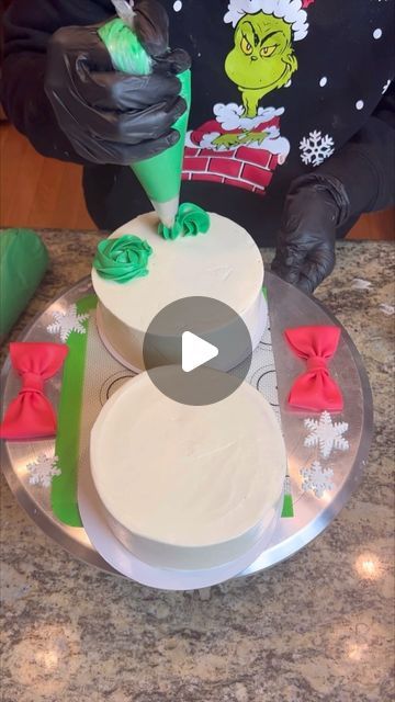 a person decorating a christmas cake with green icing and red bowknots