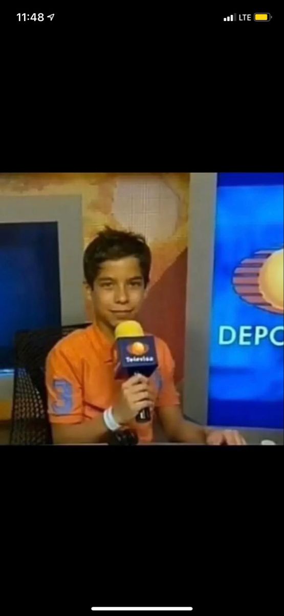 a young boy holding a microphone in front of a television screen with the caption deporte