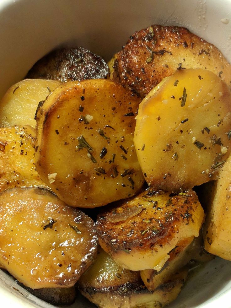 cooked potatoes in a white bowl with seasoning sprinkled on the top and sides