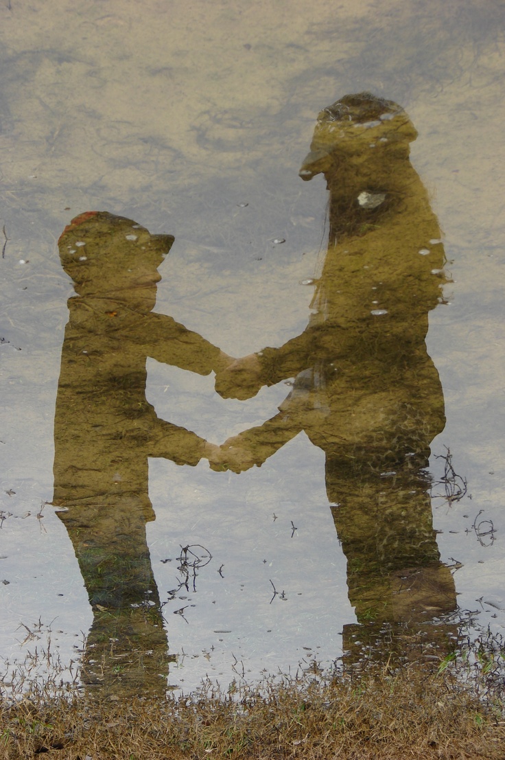 the reflection of two people shaking hands in water