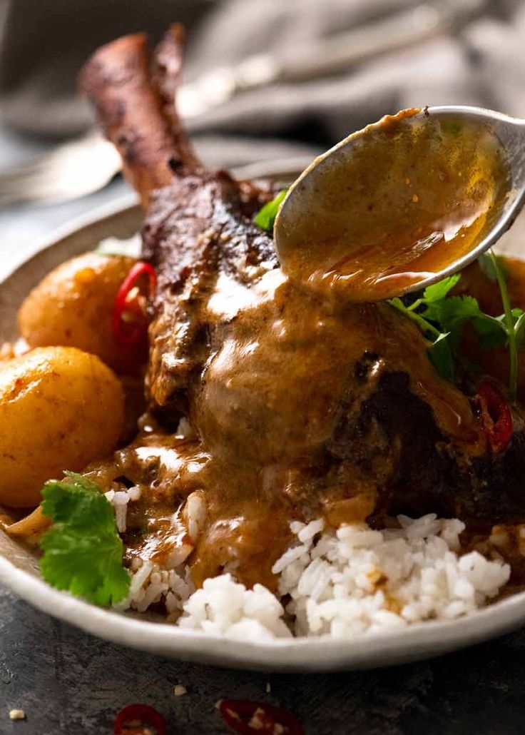 a spoon is being used to scoop some food out of a bowl with rice and meat