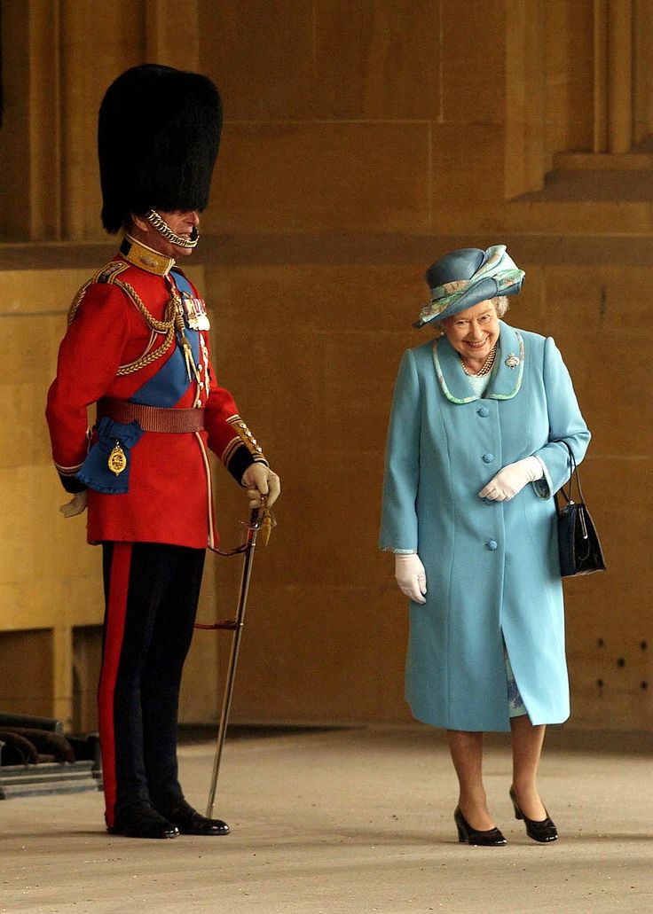 queen elizabeth and the duke of edinburgh stand in front of an official guard at buckingham palace