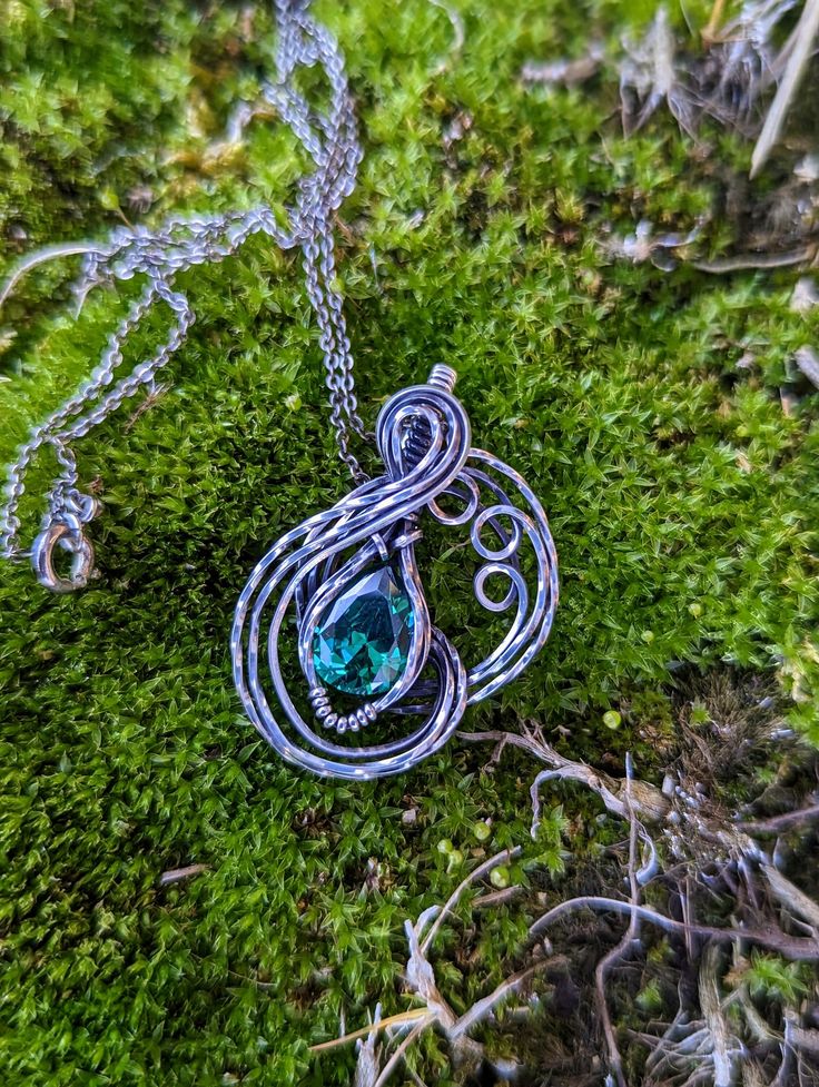 I made this necklace this pendant some time ago, then I decided that I wanted to oxidize it to give it even more of an aged look. I wanted this to look like a piece that has seen some adventures and still shines. The cubic zirconia in this necklace is gorgeous, and so eye catching. It is a teal cubic zirconia, and looks like a very cool green color in person. I used silver filled wire for this wrap, and it turned out great. This piece, like most my work, is a one of a kind pendant. A unique stat Teardrop Shaped Silver Brass Necklace, Silver Brass Teardrop Necklace, Unique Oxidized Round Pendant Necklace, Green Oxidized Pendant Necklace, Spiritual Silver Emerald Necklace, Spiritual Silver Necklace With Emerald, Unique Oxidized Necklace For Gift, Unique Oxidized Finish Necklace For Gift, Silver Emerald Teardrop Necklace