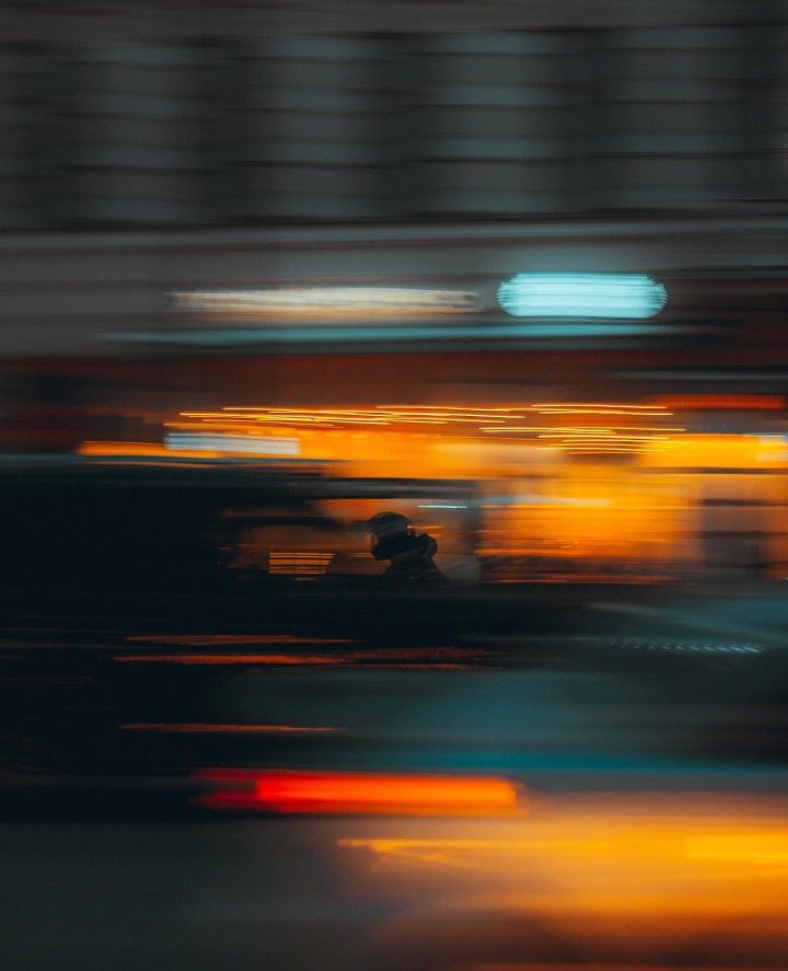 blurry image of cars driving down the road at night time with lights on them