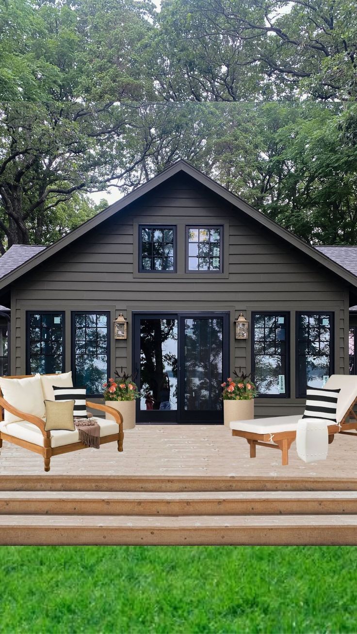 two lawn chairs sitting on top of a wooden deck next to a house with large windows