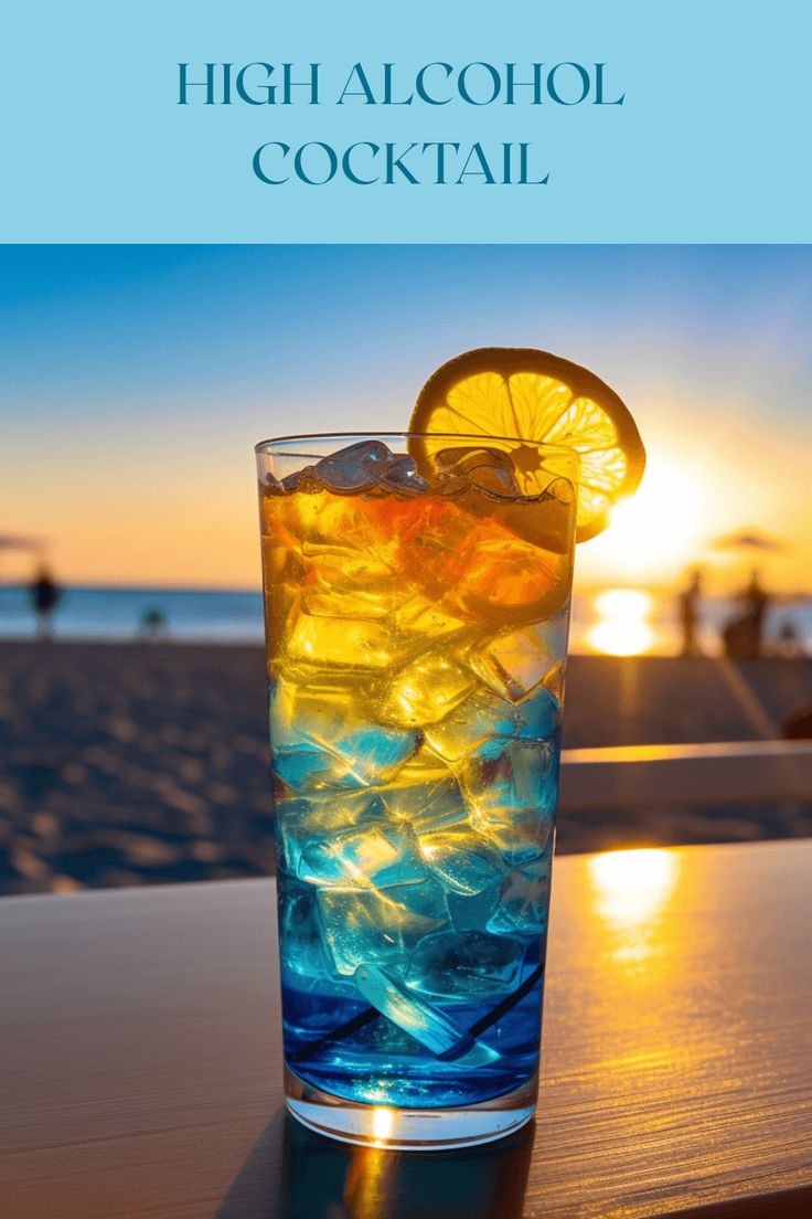 a glass filled with ice and lemon on top of a table next to the ocean