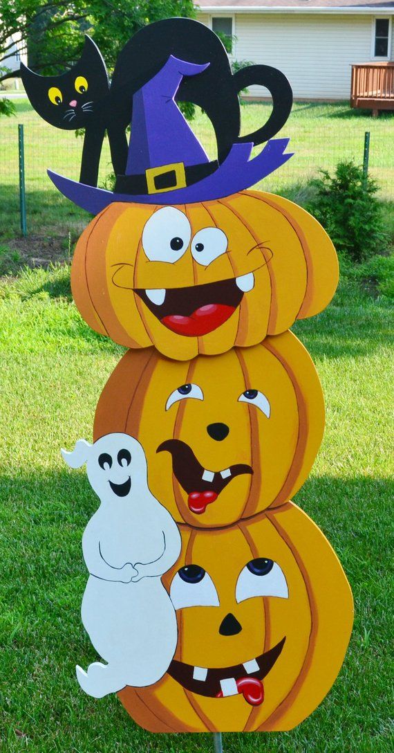 three pumpkins stacked on top of each other in front of a house with two black cats