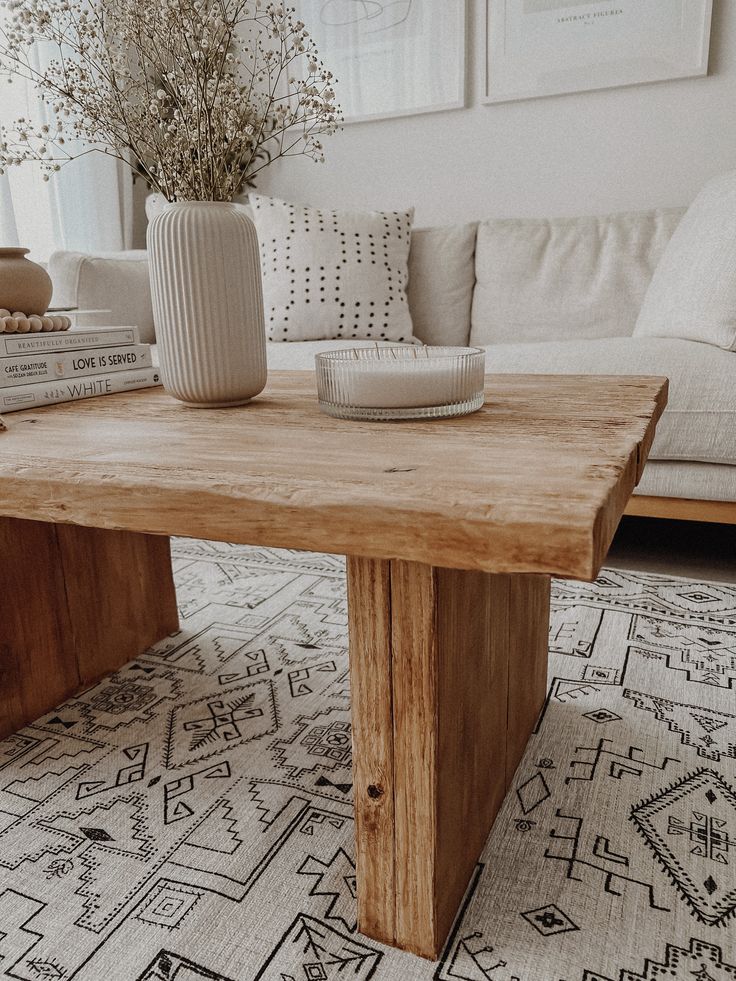 a wooden table sitting on top of a living room floor next to a white couch