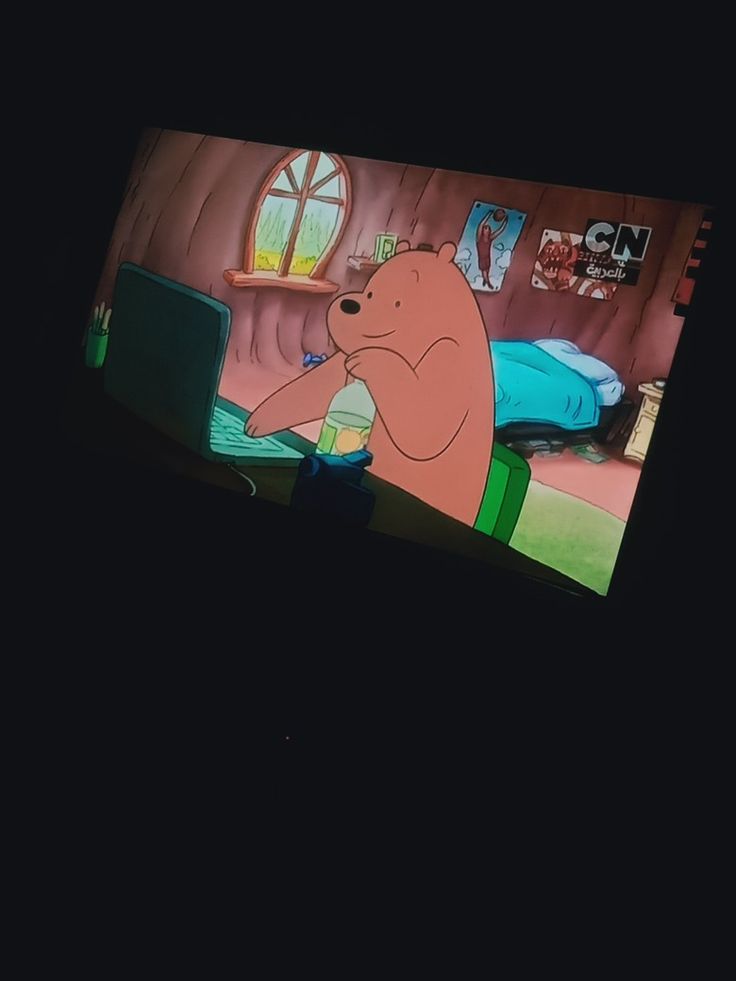 the cartoon bear is sitting in his bed and looking at something on the television screen